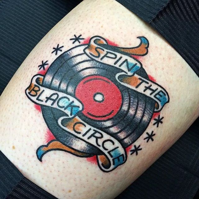 an old school style tattoo on the leg of a woman's thigh with a vinyl record