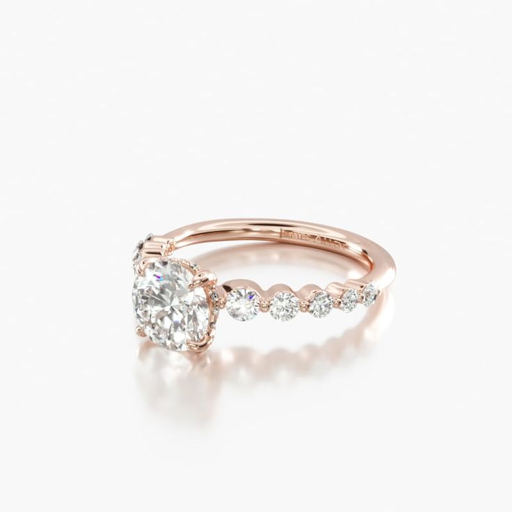 a rose gold engagement ring with an oval cut diamond in the center and side stones