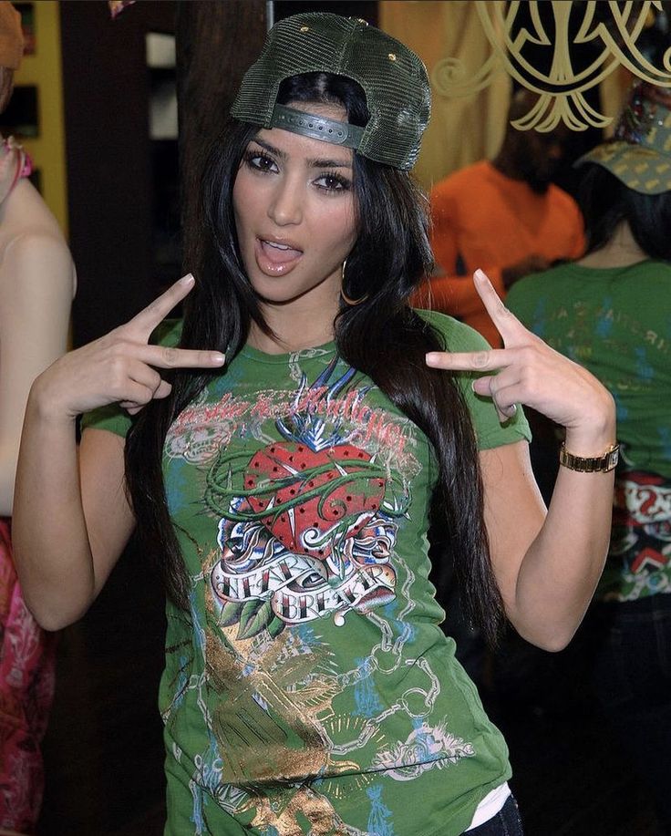 a woman wearing a green shirt and hat making the peace sign