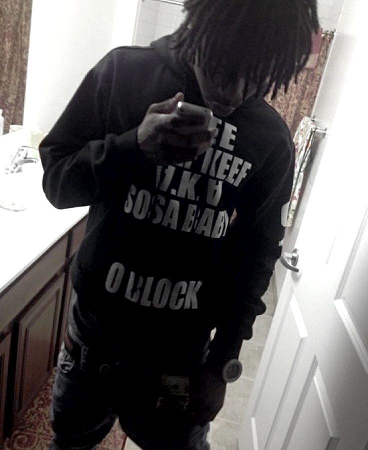 a man standing in front of a bathroom mirror looking at his cell phone while wearing a hoodie