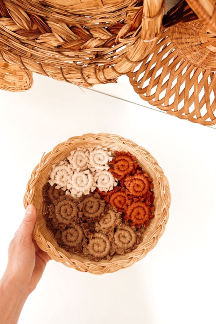 a person holding a basket filled with different types of cookies in it's hands