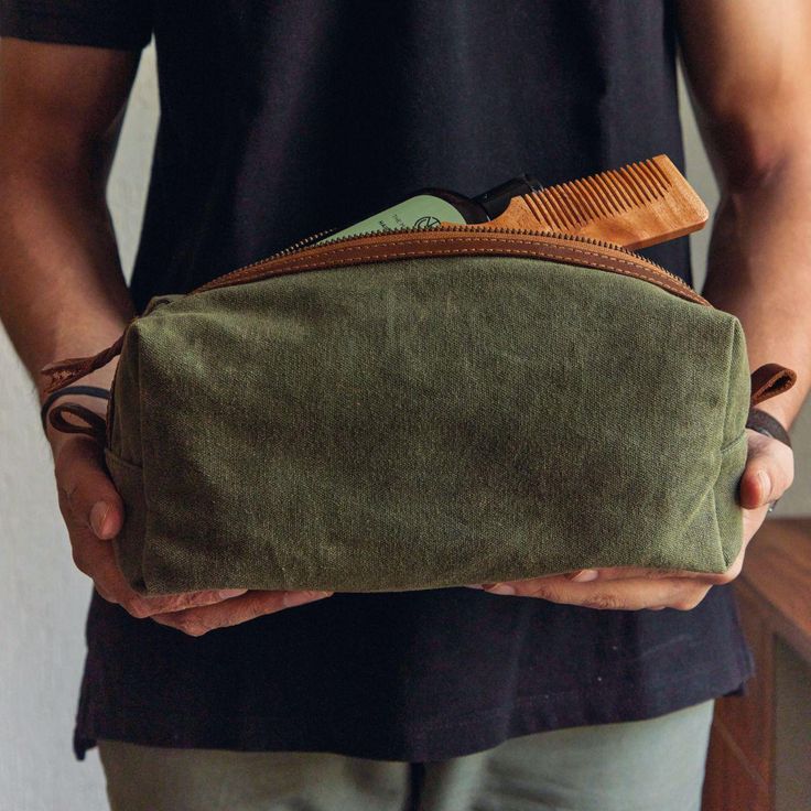 a man is holding a green pouch with some items in it's pockets and his hands are on the ground