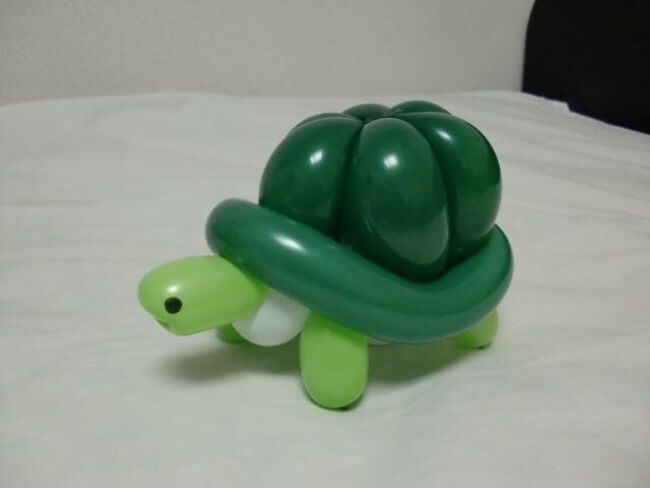 a green turtle toy sitting on top of a white bed