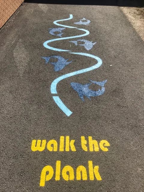 the sidewalk is painted with blue and yellow chalk on it, which says walk the plank