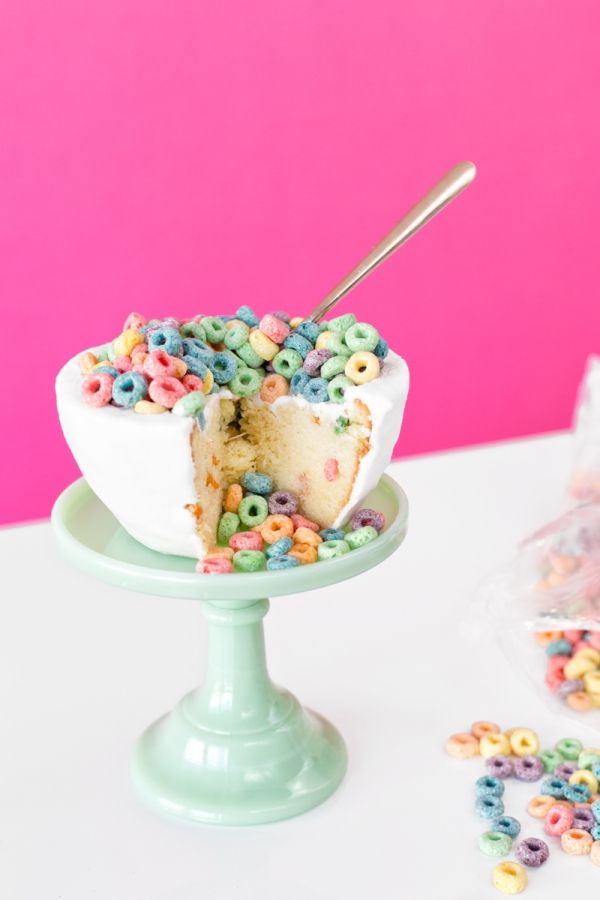 a cake with cereal toppings and a slice taken out of it on a plate