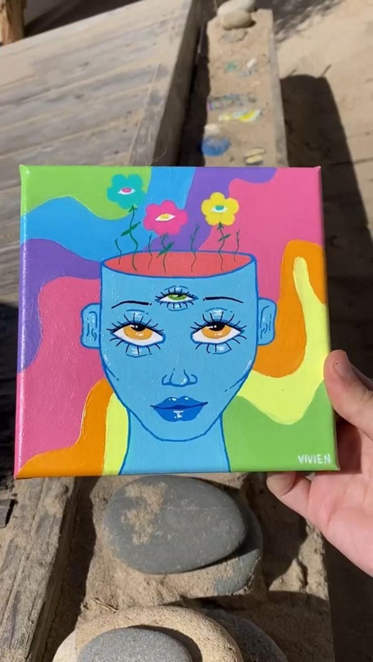 a person holding up a colorful painting with flowers in their hair on it's head