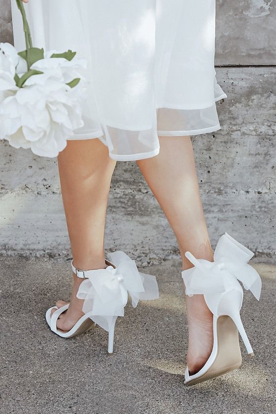 a woman's feet wearing white shoes and holding a flower