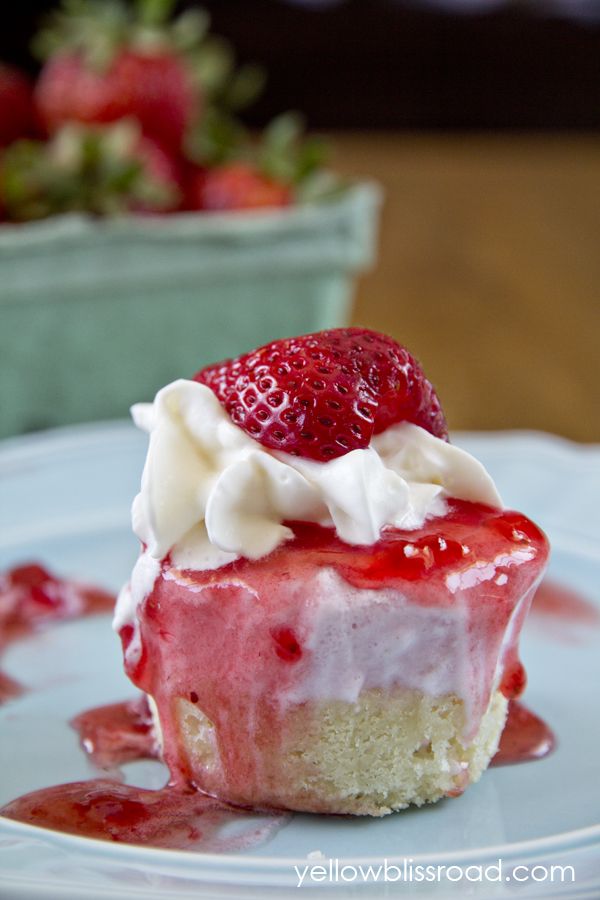 a piece of strawberry cheesecake with whipped cream and strawberries on top, sitting on a plate