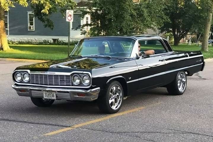 an old black car is parked on the street