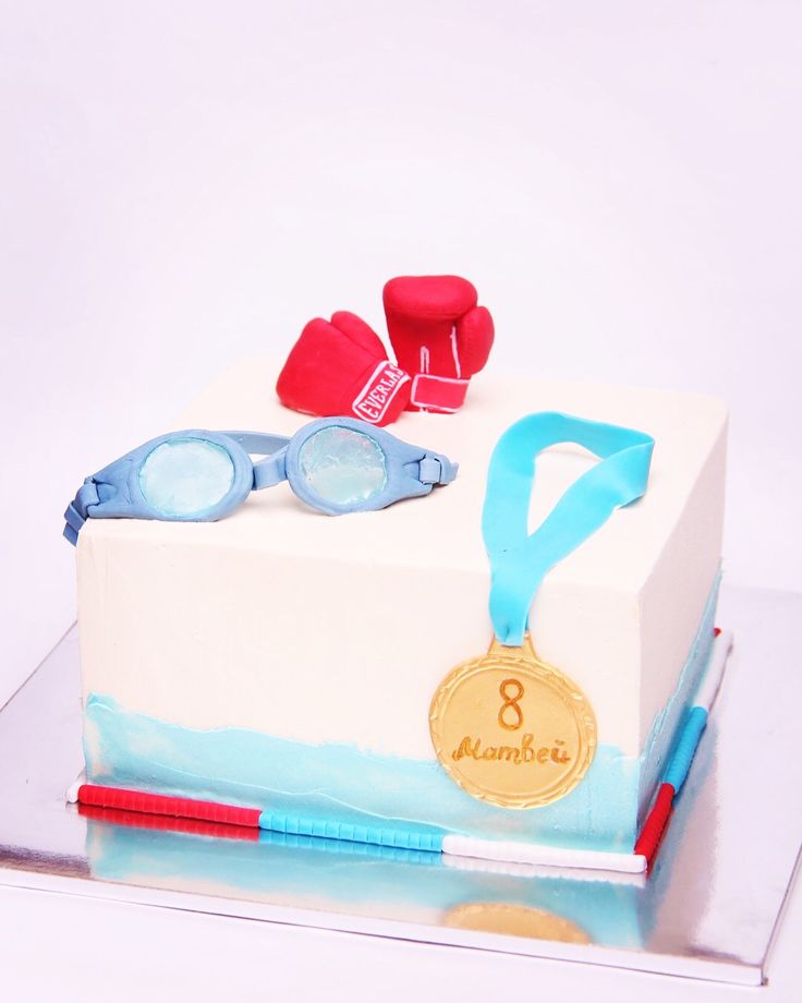 a cake decorated with swimming goggles and an olympic medal is shown in front of a white background