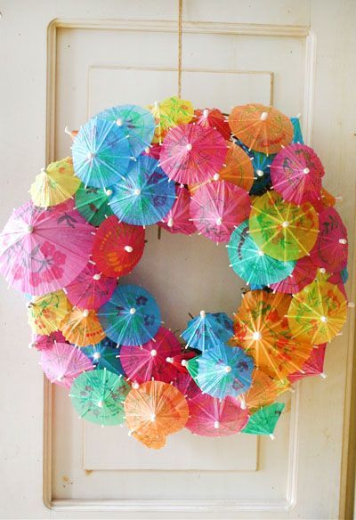 a wreath made out of umbrellas hanging from the side of a door with lights on it