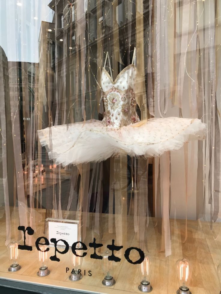 a window display with a mannequin dressed in a white dress and tiara