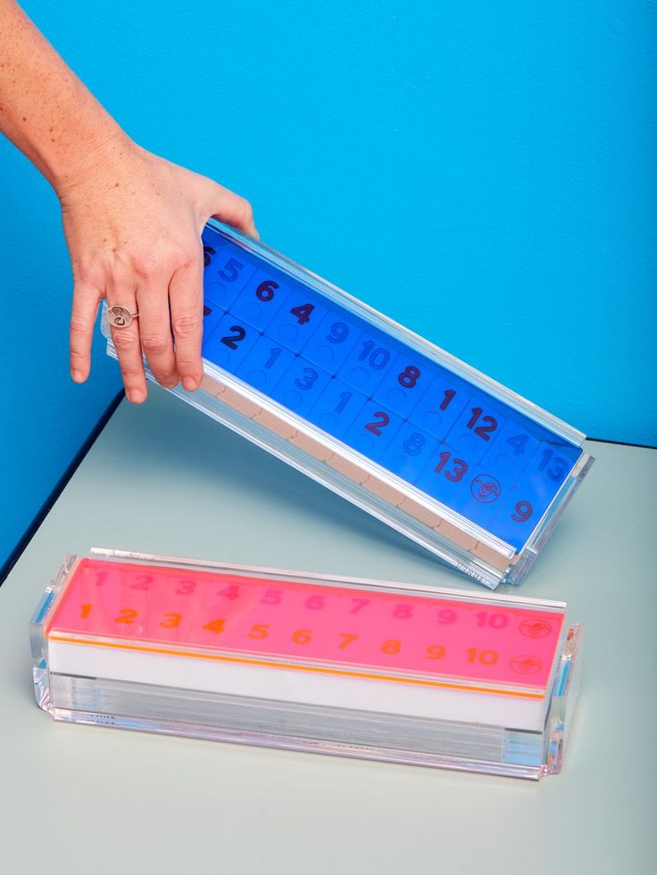 a person is holding a blue and pink calculator with numbers on the side