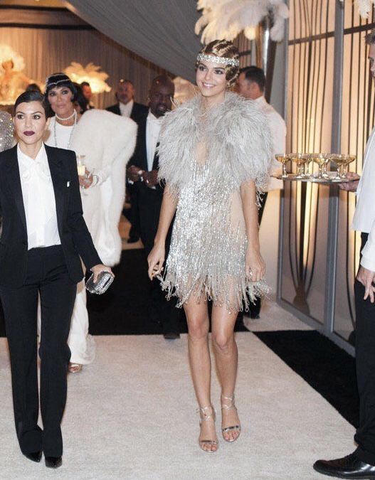 two women dressed in flap suits and feathered hats walk down the aisle at an event