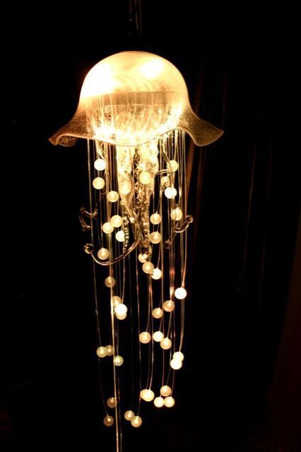 a light that is on top of a stand with beads hanging from it's sides