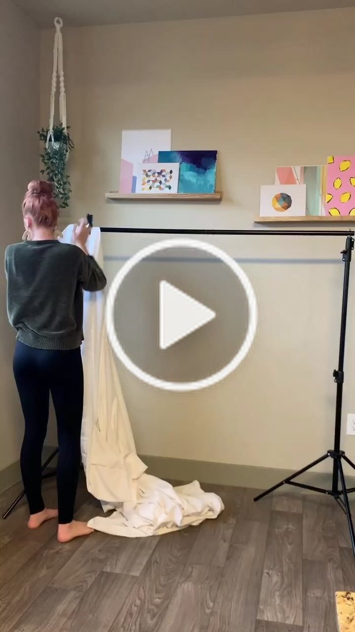 a woman standing in front of a camera holding a white sheet and looking at it