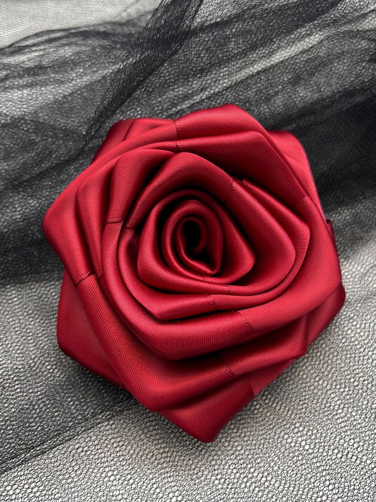 a red rose sitting on top of a piece of sheer fabric next to a black net