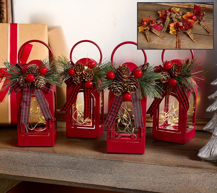 three red lanterns decorated with pine cones and bows are sitting on a mantle next to a christmas tree