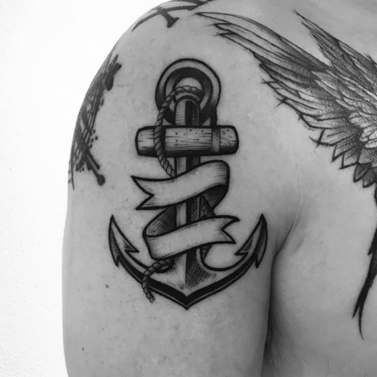 a man with an anchor and wings tattoo on his shoulder