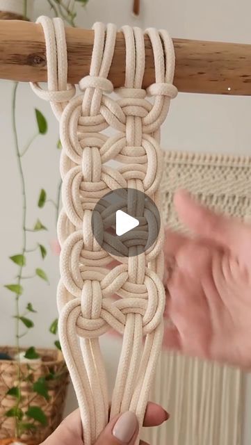 someone is holding up a piece of art made out of rope and yarn with a video playing on it