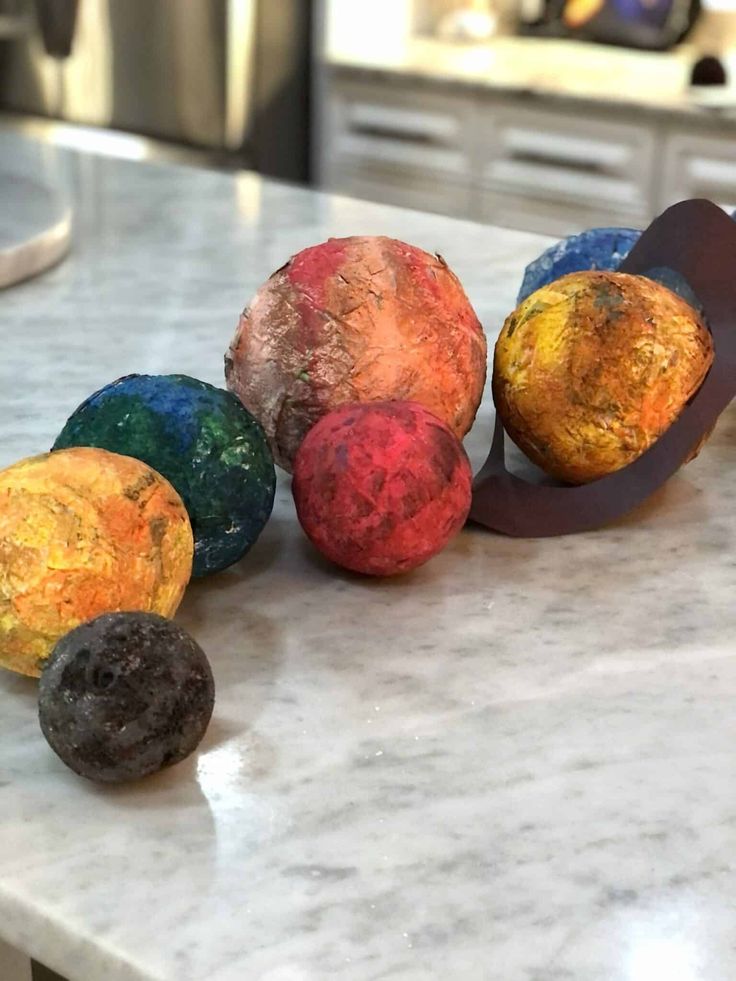 five different colored balls on a counter top in the middle of some sort of art