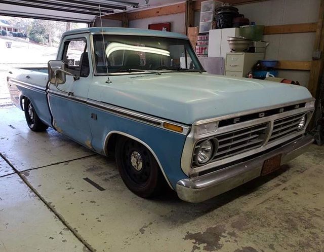 an old blue truck parked in a garage