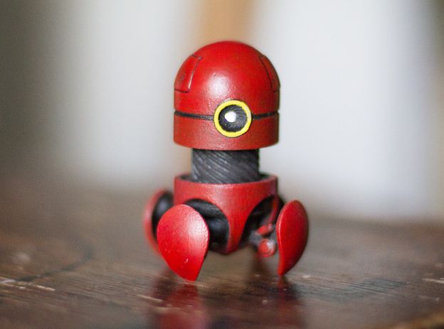 a red robot toy sitting on top of a wooden table