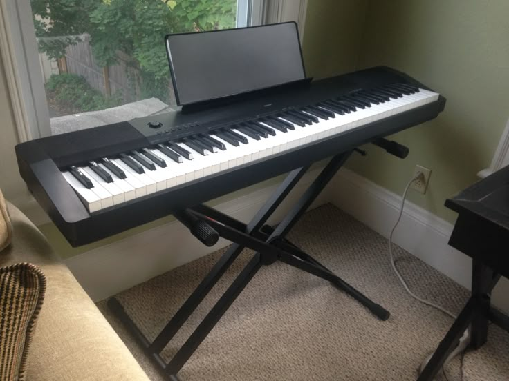 a keyboard sitting in front of a window with a laptop on it's stand