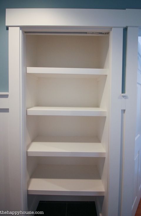 an empty closet with white shelves and blue walls