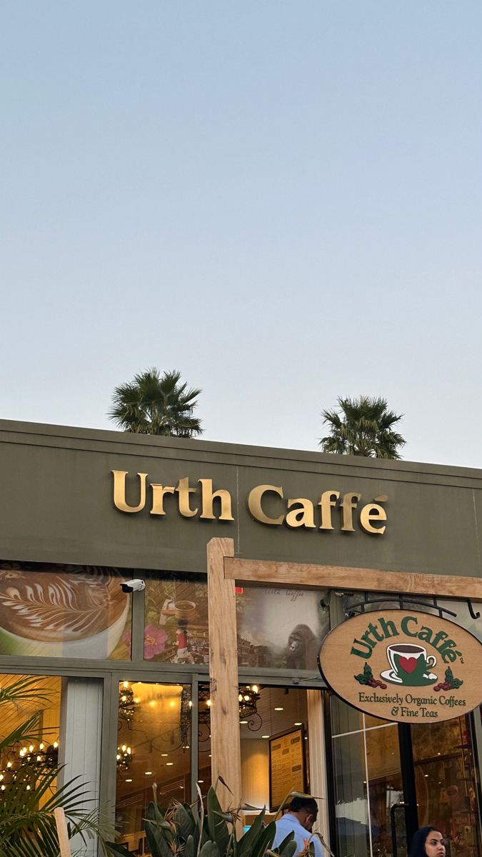 the outside of a coffee shop with people walking in front of it and palm trees