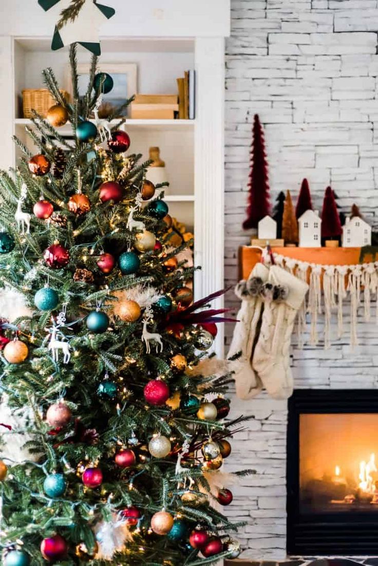 a decorated christmas tree in front of a fireplace