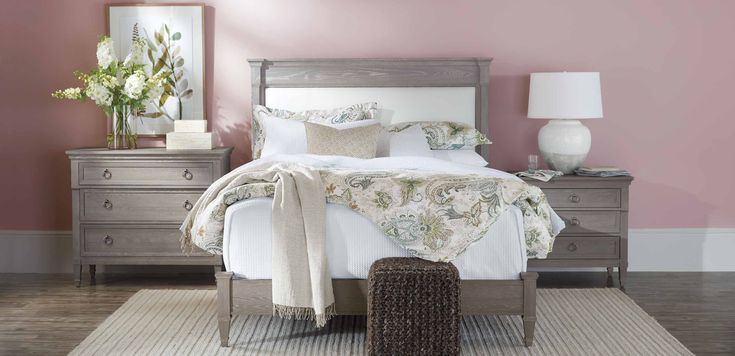 a bedroom with pink walls and white bedding in the center, along with two nightstands