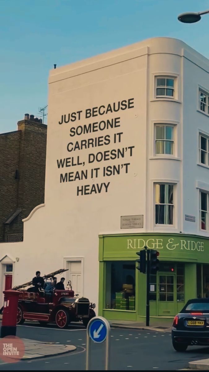 an advertisement on the side of a building in london, england that reads just because someone carries it well, doesn't mean it isn't heavy