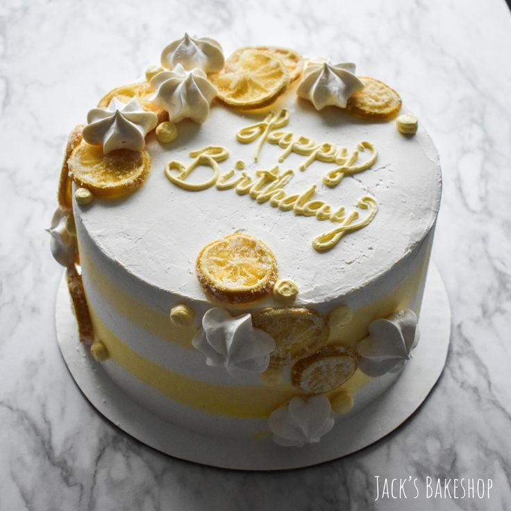 a white and yellow birthday cake sitting on top of a marble countertop covered in frosting