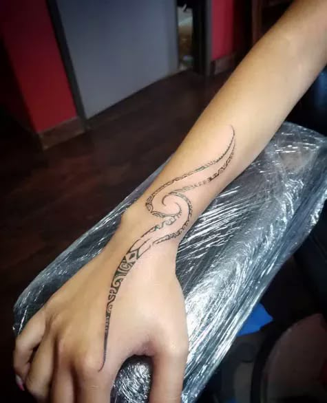 a woman's hand with a tattoo on it sitting on top of a table