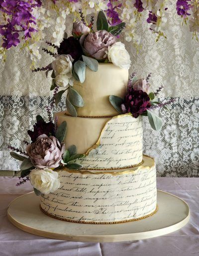 a three tiered cake with flowers and writing on the side is sitting on a table