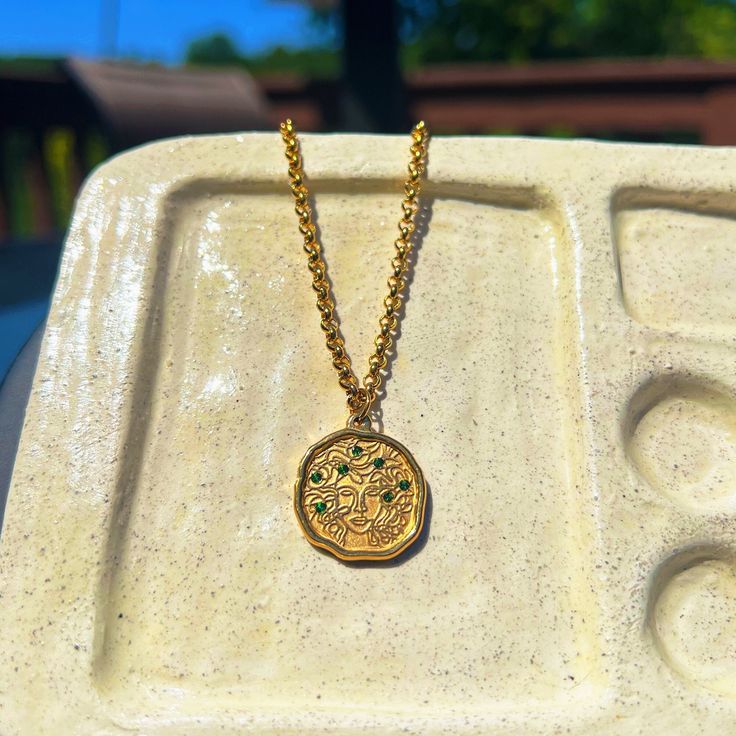 a gold necklace with an intricate design on it is sitting in a white tray outside