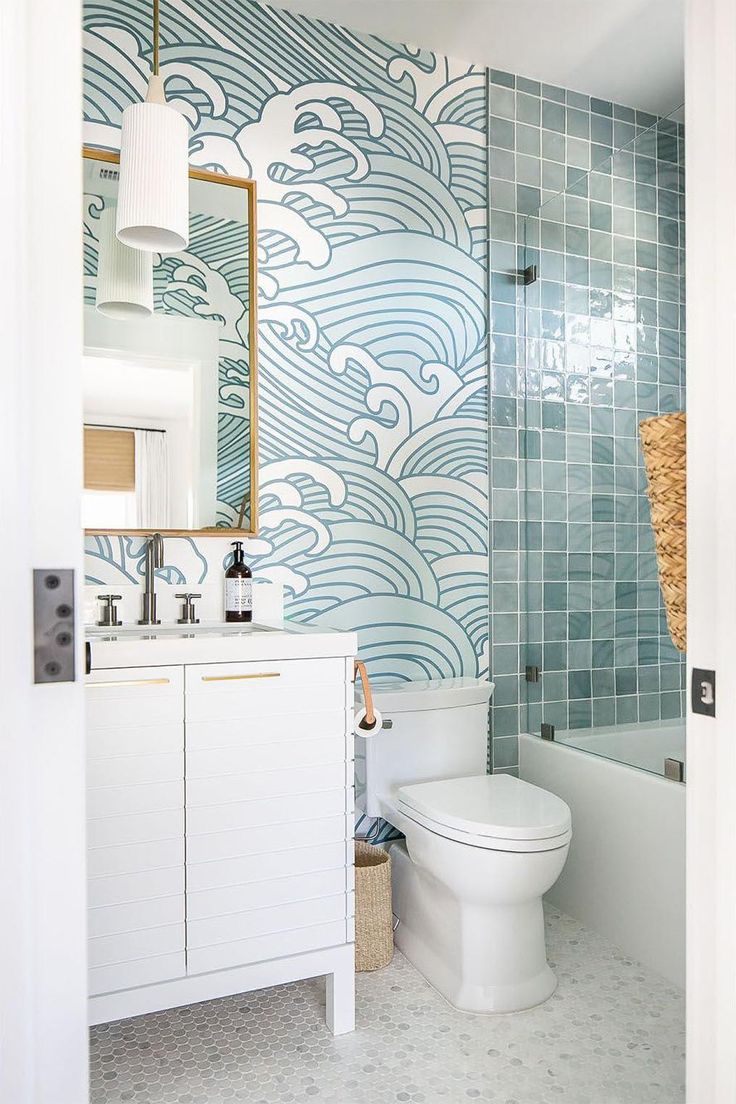 a white toilet sitting next to a bath tub in a bathroom under a mirror on top of a wall