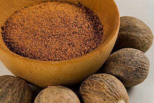 nutmeal powder in a wooden bowl surrounded by nuts