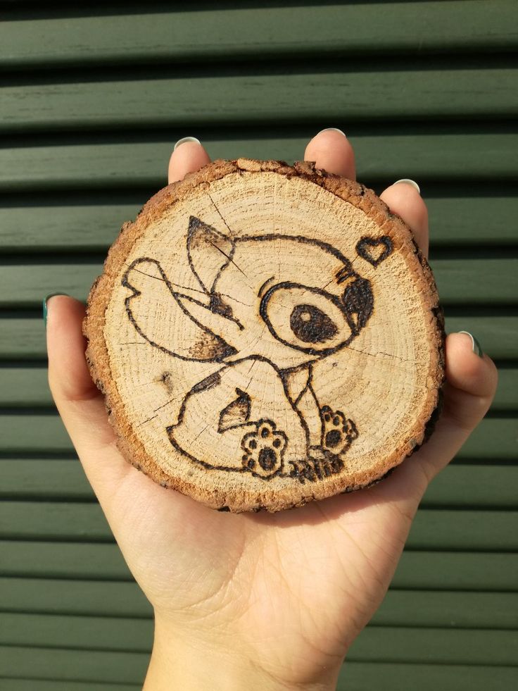 a hand holding a piece of wood with an image of a cartoon character on it