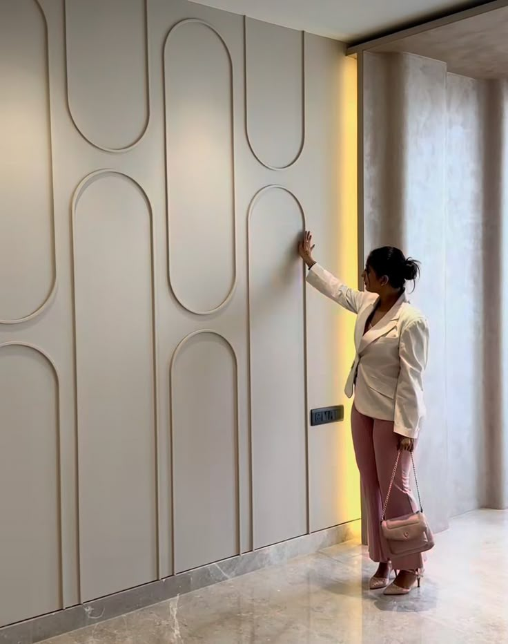 a woman standing in front of a white wall holding onto a pink purse and writing on it