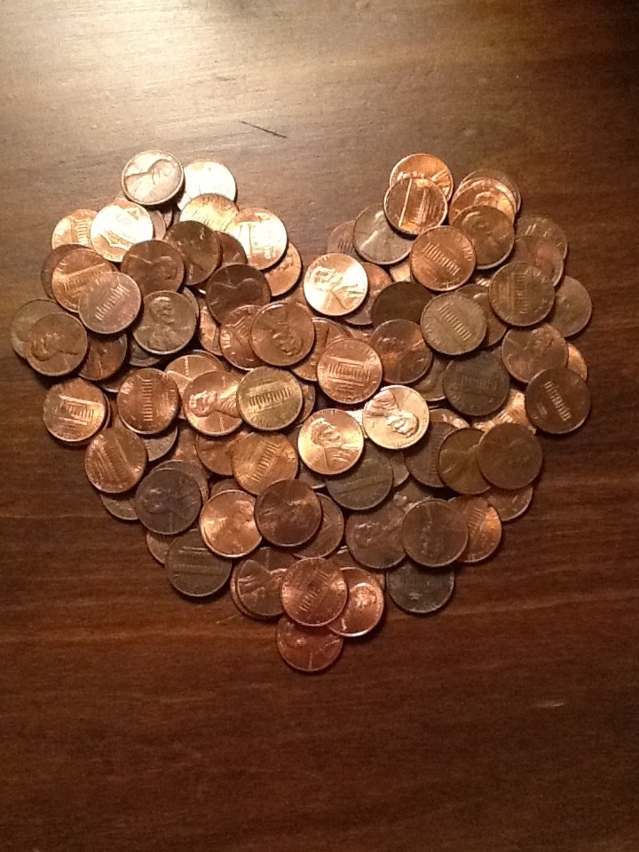 a heart made out of pennets sitting on top of a wooden table