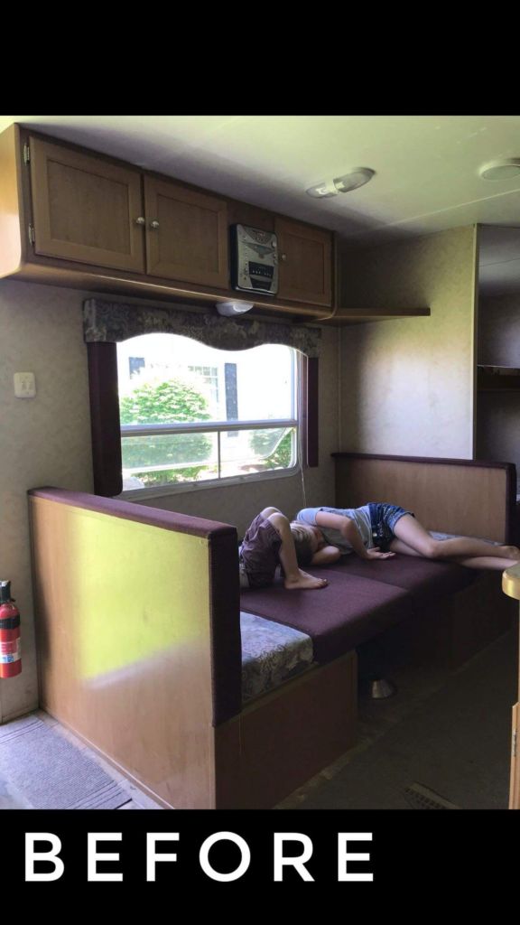 a man laying on top of a bed next to a window in a room filled with cabinets