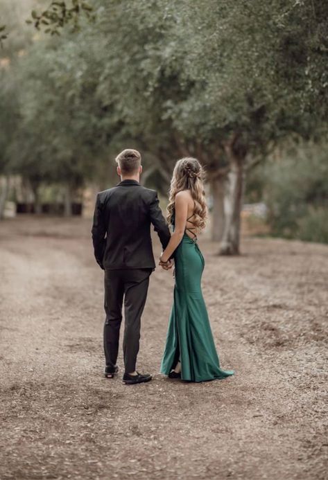 a man and woman walking down a dirt road holding hands