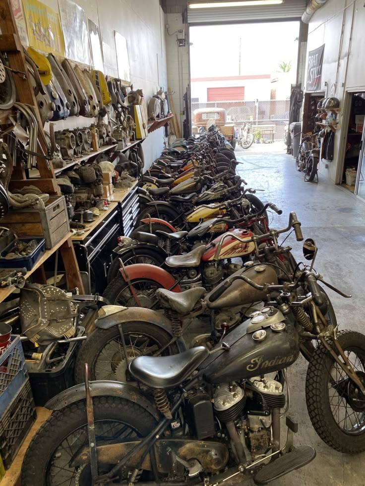 many motorcycles are lined up in a garage with shelves full of tools and other items