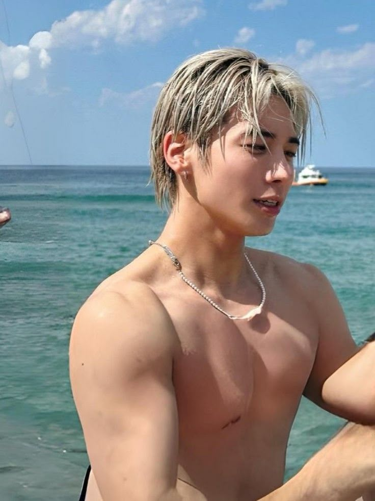 a shirtless young man standing in the ocean