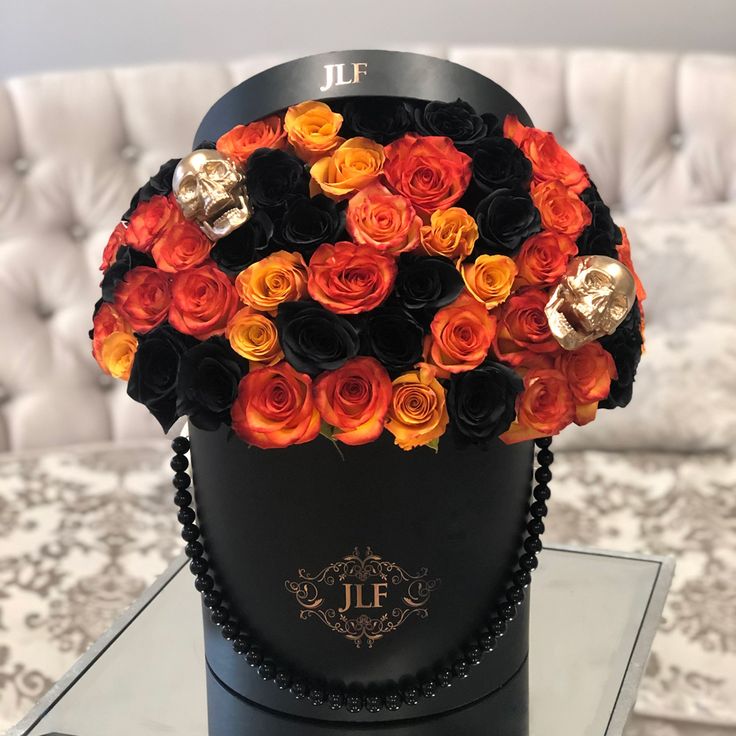 a black hat with orange and red roses in it sitting on a table next to a couch