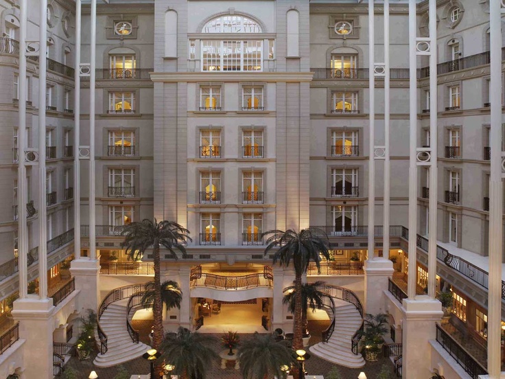 the inside of a large building with palm trees in front of it and stairs leading up to the second floor