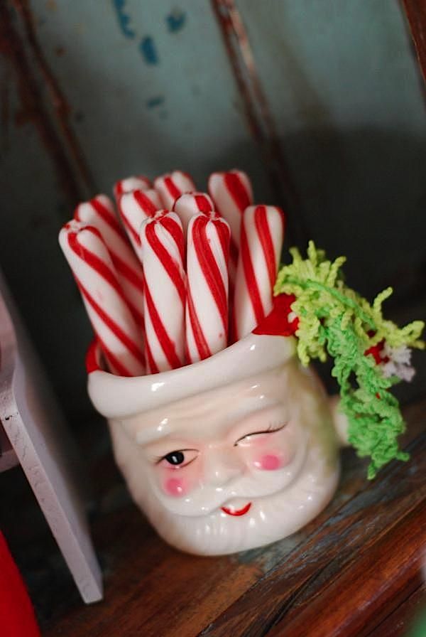 some candy canes are in a santa claus's hat on top of a shelf