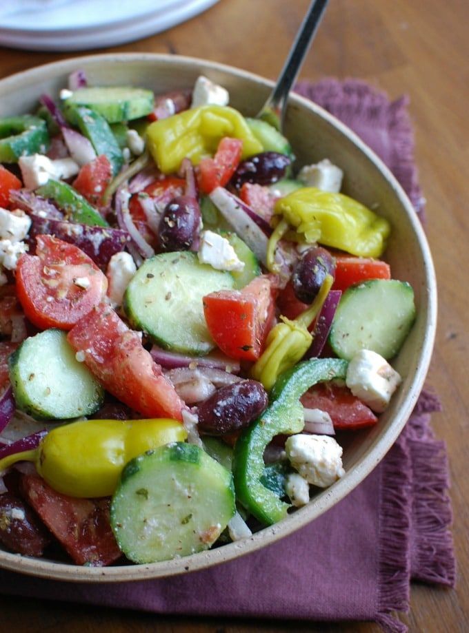 a salad with cucumbers, tomatoes, olives, and feta cheese